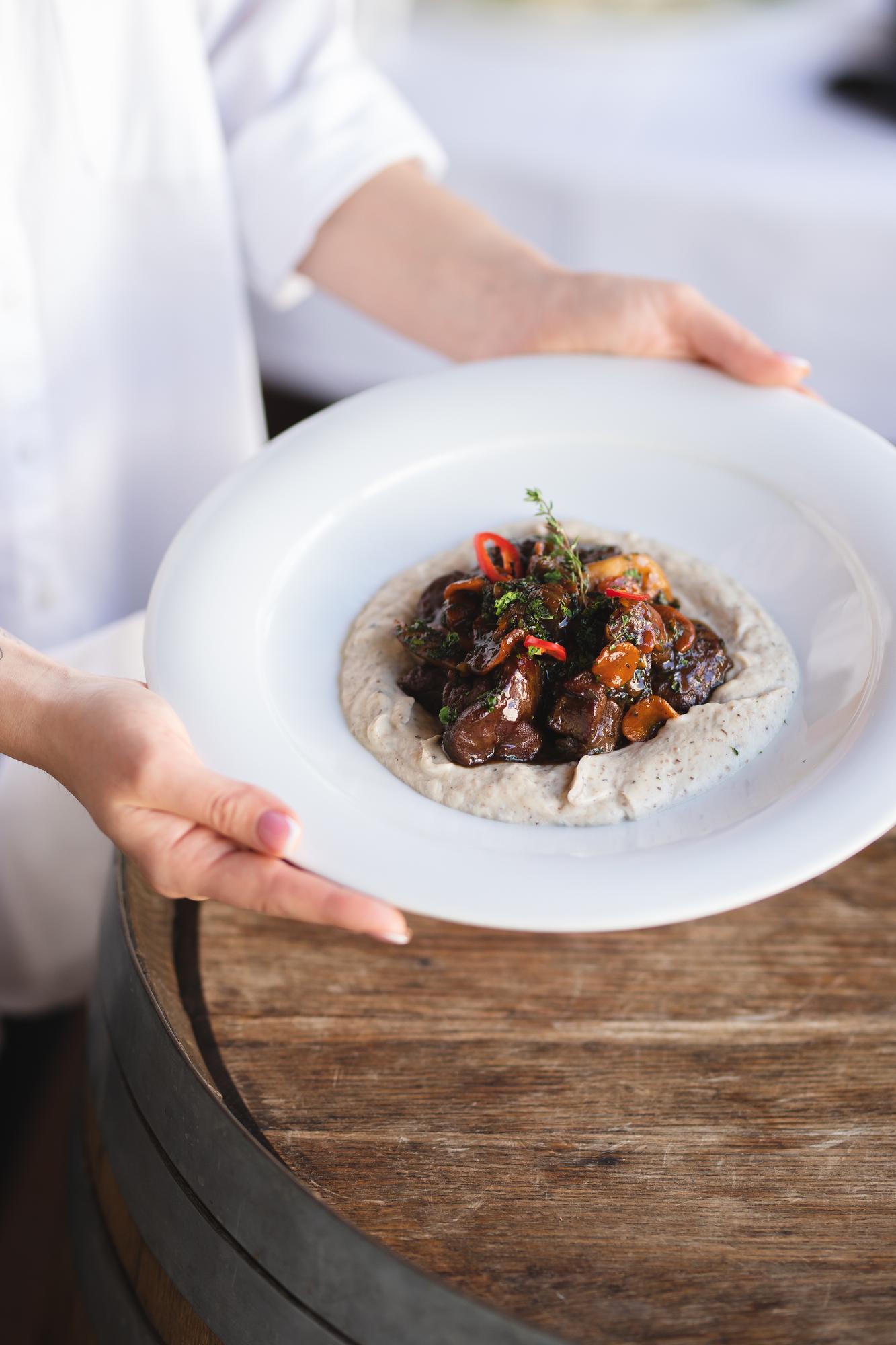 chef arranging plated dish on wooden table